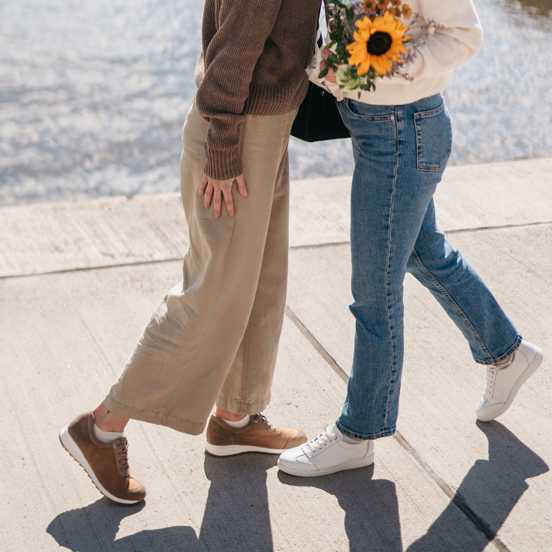 Kaksi ihmistä tervehtii toisiaan ulkona jalassaan naisten tennarit.