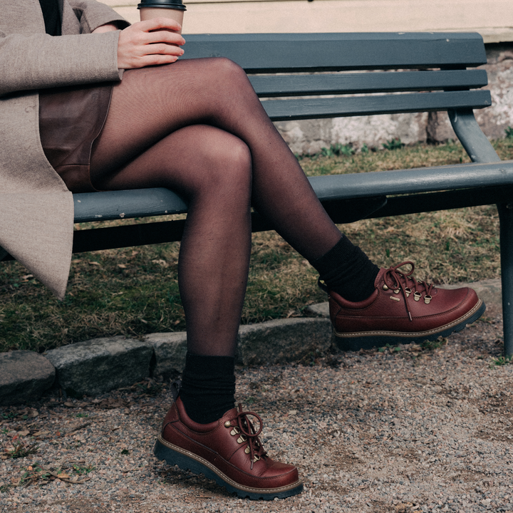 Henkilö istuu penkillä jalassaan naisten matalat kävelykengät.